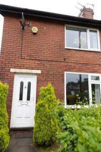 a red brick house with a white door at The Standhouse Radcliffe in Radcliffe