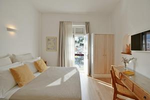 een witte slaapkamer met een bed en een schuifdeur van glas bij NESEA VIEW Boutique Apartments in Hydra