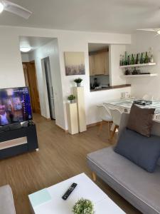 a living room with a couch and a table and a kitchen at PLAYA ALMARDA CORINTO, PISCINA, WIFI,2 TERRAZAS, BARBACOA,TRANQUILo in Sagunto