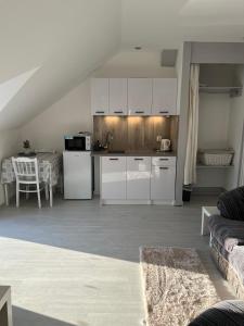 a kitchen and living room with white cabinets and a table at Pensjonat nad jeziorem Lakeside in Brodnica Dolna