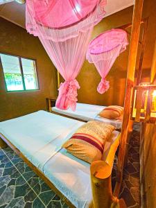 two beds in a room with pink mosquito nets at Elephant paradise Safari resort in Udawalawe