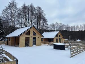 two buildings in the snow with trees in the background at Osada Leonówka in Leonów