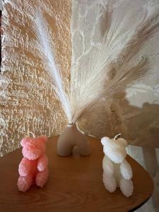 two stuffed animals sitting on a table next to a feather at Écrin Secret - Suite troglodyte avec spa in Pia