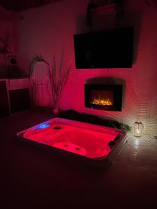 a hot tub in a room with a fireplace at Écrin Secret - Suite troglodyte avec spa in Pia +10 photos