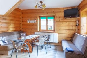 a living room with a table and chairs and a couch at Drewniany Domek in Witów