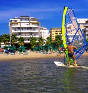 a man on a surfboard with a sail on the beach at Hotel Vila Lule in Durrës