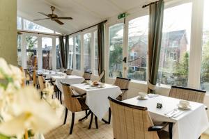 a restaurant with white tables and chairs and windows at The Falcon Hotel in Farnborough