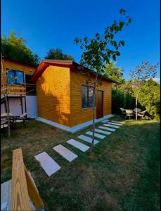 a small yellow house with a tree in the yard at Berat Hill Cabins in Berat