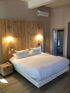 a bedroom with a large white bed with a wooden wall at Appartement des carassins in Saint-Rémy-de-Provence