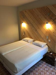 a large bed in a room with a wooden wall at Appartement des carassins in Saint-Rémy-de-Provence