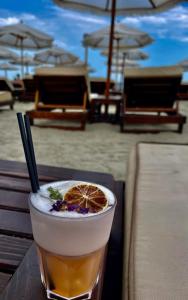a drink with an orange slice on a table at the beach at VCV Apartments in Mamaia Sat/Năvodari