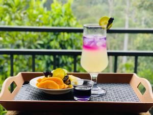 a drink and a bowl of fruit on a table at Ella White Tea Garden Hotel in Ella