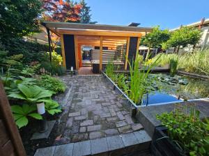 ein kleines Haus mit einem Teich im Garten in der Unterkunft Artz of Nature in Emmen