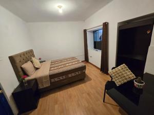 a bedroom with a bed and a couch and a chair at Magnolia Andina Hostel in Cusco