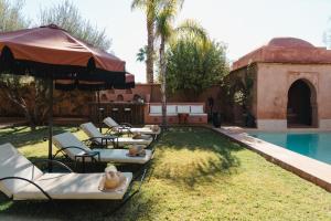 a group of lounge chairs and an umbrella next to a pool at Villa Riad Marrakech in Najem