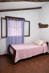a bed in a room with a blue curtain at El Bosque de Simba - Casa in La Estancia