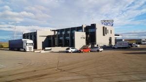 un grand bâtiment avec des voitures garées dans un parking dans l'établissement Hotel Area de Servicio Los Chopos, à Villaherreros