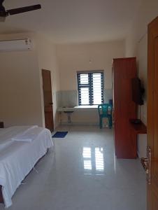 a bedroom with a bed and a table and a window at PURAYIL Rooms in Kozhikode