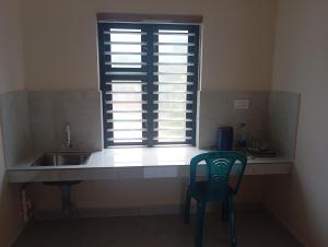 a kitchen with a sink and a window with a chair at PURAYIL Rooms in Kozhikode
