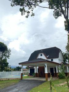 a white house with a black roof at La villa June by Juniar Place in Kampong Ulu Pegoh