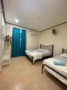 a room with two beds and a blue curtain at La villa June by Juniar Place in Kampong Ulu Pegoh +2 photos
