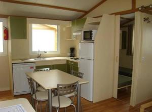 a kitchen with a table and chairs and a refrigerator at ZEcamping 4 animaux acceptés hammam sauna piscine et soirées animées in Espelette