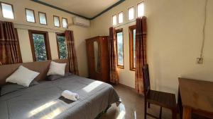 a bedroom with a bed and some windows at Chik Nories in Labuan Bajo