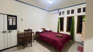 a bedroom with a bed and a desk and some windows at Chik Nories in Labuan Bajo