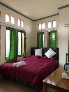 a bedroom with a large red bed with green curtains at Chik Nories in Labuan Bajo