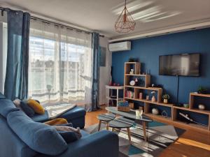 a blue living room with a couch and a tv at Appartement d'exception spacieux, 2 chambres, terrasse privée, vue Cathédrale imprenable in Strasbourg