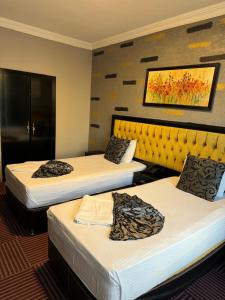 a hotel room with three beds and a yellow headboard at Ankara Efes Otel in Altındağ