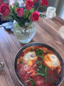 a bowl of food on a table with a vase of roses at Maison Des Glycines in Droux +19 photos
