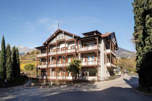 a large wooden building with trees in front of it at Villa Rosengarten Guesthouse in Merano