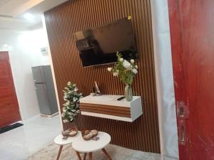 a room with a television and a table with flowers on it at Wamis serviced apartments in Solwezi