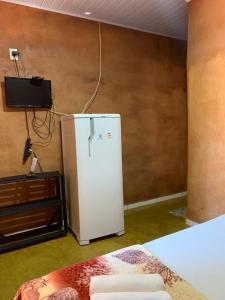 a white refrigerator in a room with a tv at Recanto do Vale in Pirenópolis