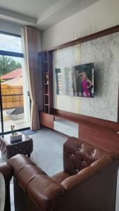 a living room with a leather couch and a tv at Pana Villa Koh Lanta in Ban Ai Dao