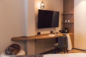 a room with a desk with a television on a wall at Das Liebener 4 Sterne Superior - ADULTS ONLY! in Obergurgl