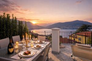 a table with plates of food on a balcony with a sunset at Villa Miranda Luxury Como Lake View Penthouse with Panoramic Terrace in Como