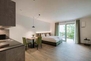 a bedroom with a bed and a table and a kitchen at Villa Rosengarten Guesthouse in Merano