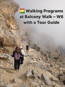 a group of people walking up a rocky mountain at house of the cloud jabal shams in Sa‘ab Banī Khamīs