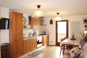 a kitchen with wooden cabinets and a table and a dining room at CAV MES VALLEES Torgnon Vda in Torgnon
