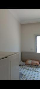 a white bedroom with a bed and a window at Canarya compound in 6th Of October