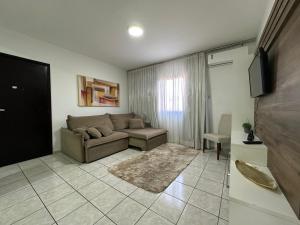 a living room with a couch and a tv at Apartamentos Nadai 201 in Foz do Iguaçu