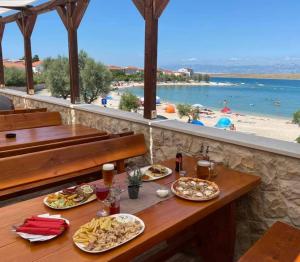 a table with plates of food and a view of a beach at Apartments Adria in Vir