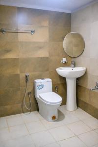 a bathroom with a toilet and a sink and a mirror at Hotel Sakura Inn in Hosūr +16 photos