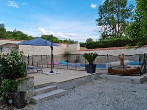 a patio with an umbrella next to a pool at Prouyssou in Beauville