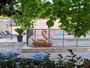 a sculpture of a swan sitting in a fence at Prouyssou in Beauville