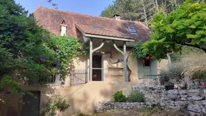 a small house with a window and a stone wall at La Fontaine du Peuch in Plazac