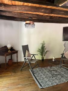 a living room with chairs and a table and a rug at La Fontaine du Peuch in Plazac