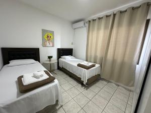 a bedroom with two beds with towels on them at Apartamentos Nadai 201 in Foz do Iguaçu